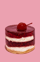 Sweet cherry on the cake in red and white colour and light biscuit on pastel pink sunlit background. Minimal food cheesecake aesthetic concept.