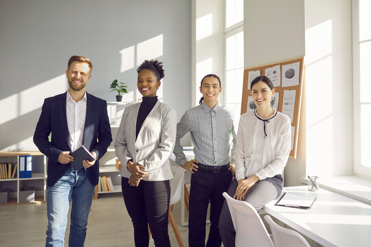 Business international team, mixed race office workers concept. Smiling positive office specialists of various nationalities standing looking at camera together in office during meeting