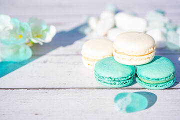 Selective focus. Turquoise and white macarons on light wooden background. French Pastel Macaroons. Blurred focus