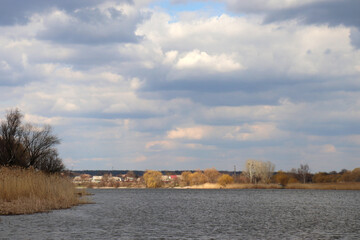 Fototapeta premium Panoramic view of the river. Spring landscape with river and cloudy sky. Stormy windy weather