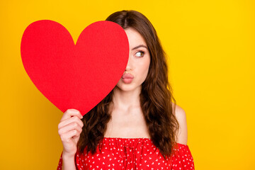 Photo of adorable lady hand hold heart symbol postcard kiss lips look empty space isolated on yellow color background