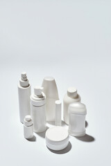 Different white bottles and containers for hygiene, health and beauty products isolated over white background with reflection