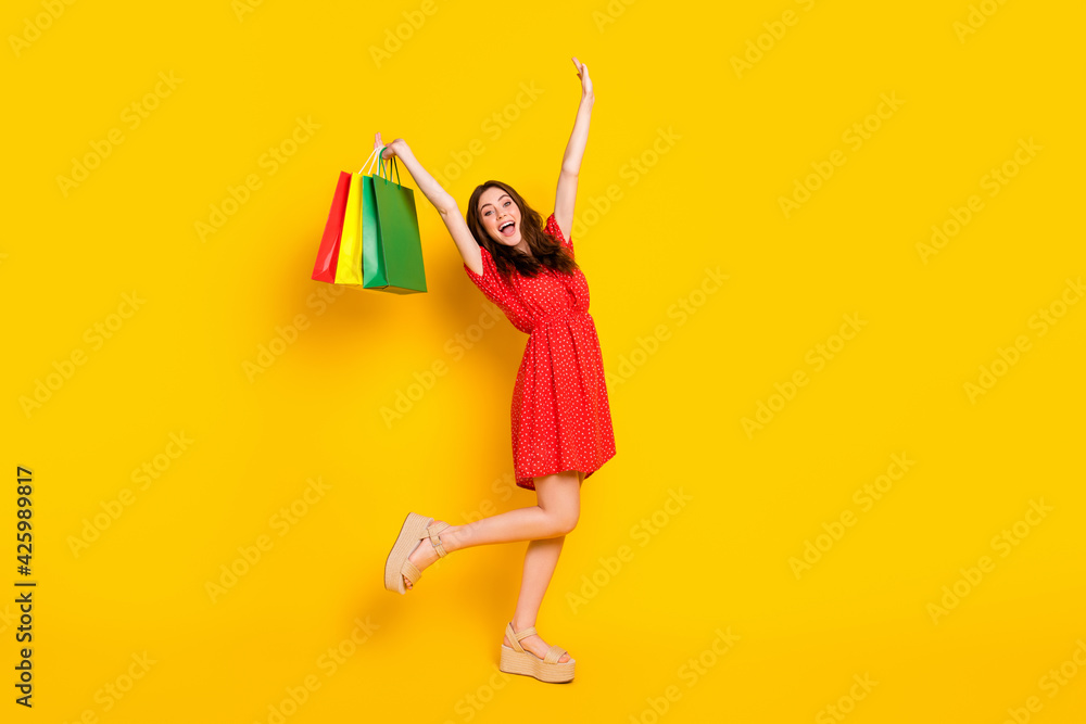 Wall mural full size photo of carefree cheerful lady open mouth raise arms bags have fun isolated on yellow col