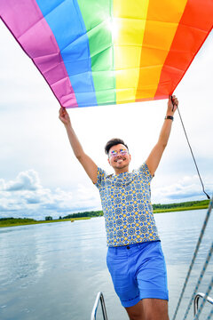 young pretty gay man smile and hold rainbow flag