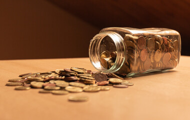 Half empty money jar with coins over the table. Save money concept banner.