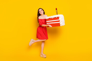 Full body profile side photo of young cheerful girl happy positive smile hold big slice birthday cake isolated over yellow color background