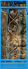 The gate is blue, with decorative twigs in the form of a vine.