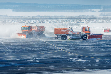 Snowplow trucks clear snowdrifts after a heavy storm blizzard at winter airport. The concept of...