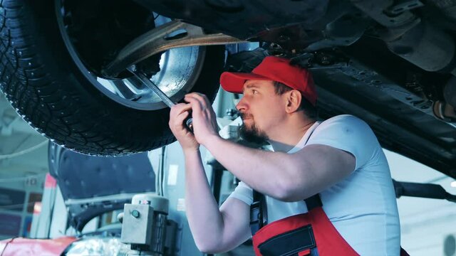 Automobile mechanic work, car service concept. Car mechanic using a wrench to tighten a wheel