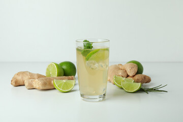 Glass of ginger beer and ingredients on white background