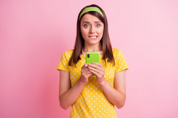 Obraz premium Photo of young attractive uncertain unsure doubtful girl bite lips hold cellphone isolated on pink color background