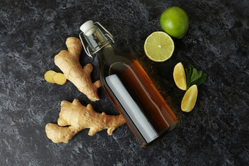 Bottle of ginger beer and ingredients on black smoky background