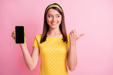 Photo of young beautiful cheerful good mood smiling girl look copyspace hold smartphone isolated on pink color background