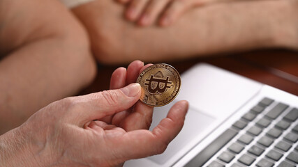 Old woman holds bitcoin coins in her hand. Retirement savings concept
