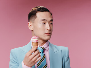 Asian guy in classic suit hairstyle ice cream pink background