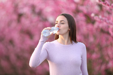 Woman drinking water from bottle in a flowered field