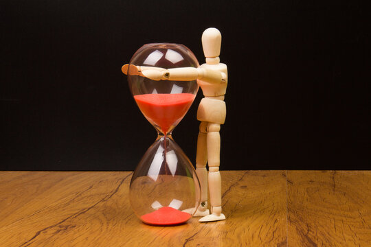 Wooden puppet and hourglass on a wooden background