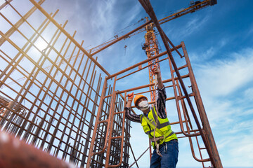 Asian worker working on steel structure at height equipment constructive at construction site. Fall arrestor device for worker with hooks for safety body harness.