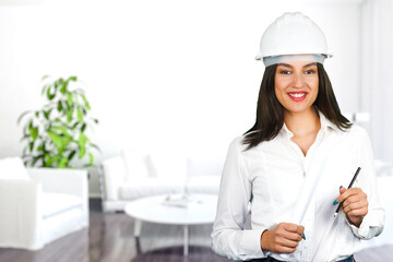 A smiling female architect with protective helmet inside a modern living room. Subject on a blurred background. Ideal shot for renovation, female work, home and interior makeover.
