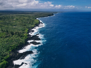 Aerial shot of waves crashing into a Hawaiian lava rock coast. drone