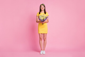 Full length body size view of attractive cheerful girl holding in hands wildflowers isolated over...