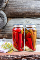 Chili peppers in a glass jar on a wooden table, homemade pickles