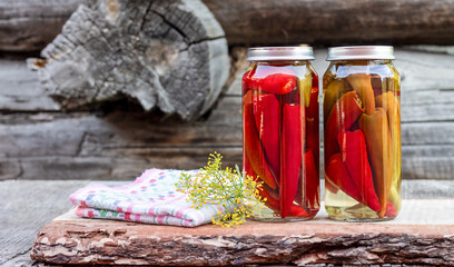 Chili peppers in a glass jar on a wooden table, homemade pickles