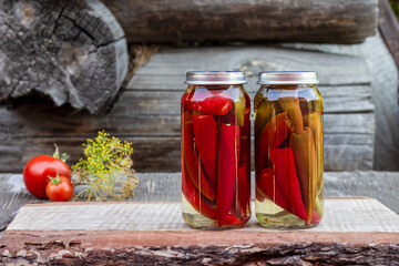 Chili peppers in a glass jar on a wooden table, homemade pickles