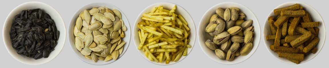 Snacks on a white background. View from above. Pistachios, pumpkin seeds, sunflower seeds, crackers, fried potatoes