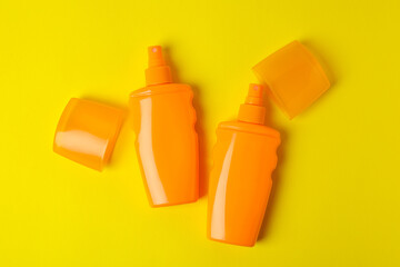 Orange bottles of sunscreen on yellow background