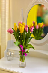 Bouquet of multicolored tulips in a jug on the table in a bright room