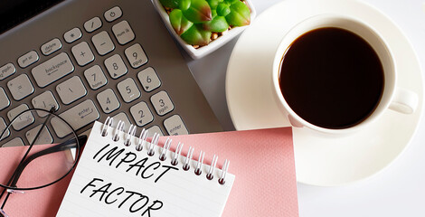 Office supplies, devices, coffee cup and glasses on white table with text IMPACT FACTOR on white background