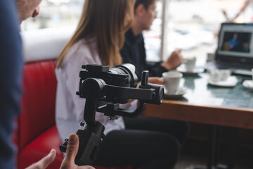 three-axis stabilizer with camera. The operator is in the process of shooting. Equipment. The work of a videographer. Cafe