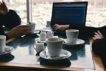 meeting in a cafe for a cup of coffee. laptop on the table. Conversation and discussion. Business and work concept. Without the visibility of faces
