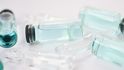 Vial vaccine, top view of glass ampoules with transparent and blue liquid lying on white background, global vaccination concept