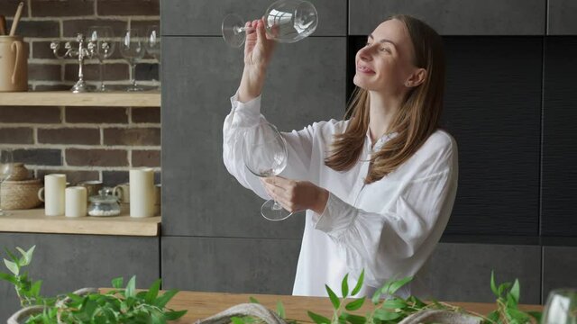 Woman takes a glass out of the dishwasher while standing in the kitchen