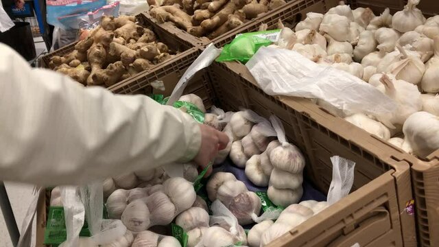 Woman selecting garlic in grocery store produce department with 4k resolution