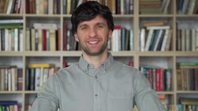 Man teacher in library looks camera communicates talk student on video call chat conference