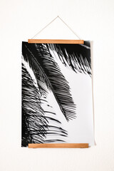 minimalistisches schwarzweiß Poster mit Palmenmotiv an einer Posterleiste aus braunem Holz...