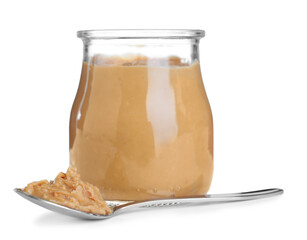 Glass jar and spoon with tasty peanut butter on white background