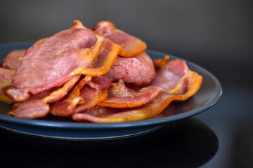 Back bacon on a blue plate. Selective focus.	
