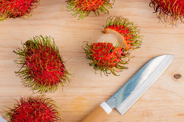 Rambutan fruit and knives on wooden table background 