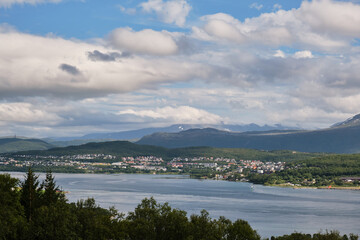 Fototapeta na wymiar View of clouds and mountains over the sea and the city in Tromso