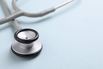 Stethoscope on light blue background, closeup. Space for text