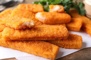 Tasty fresh fish fingers on wooden board, closeup