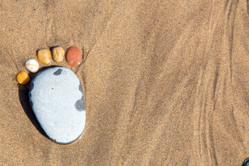 Fototapeta na wymiar Stone Feet made from pebbles on a beach