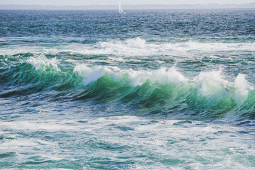Ocean waves, turquoise ocean with a sailboat in the background. Sea landscape.