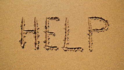 Help - inscription on the sand by the ocean.