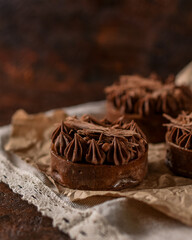 sand tartlets decorated with chocolate cream lie on craft paper on a brown background. sweet desserts for a holiday party. homemade baking