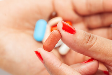 Macro Close up of medicinal or herbal multi-color tablet, capsule, and pill on a female hand palm. Top view,